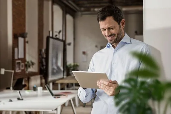 Lachender Mann mit Tablet in der Hand: Mehrheit der Mietenden plant 2026 konkrete Energiesparma&szlig;nahmen &ndash; digitale L&ouml;sungen von Techem unterst&uuml;tzen dabei