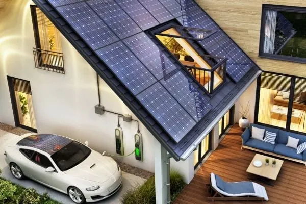 Elektroauto beim Laden an der Wallbox an einem Einfamilienhaus. Auf dem Dach eine PV-Anlage