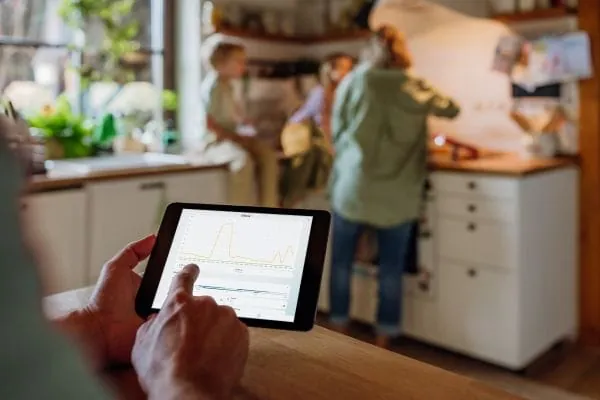 Person bedient über Tablet EMS Clee. Im Hintergrund Küchenszene