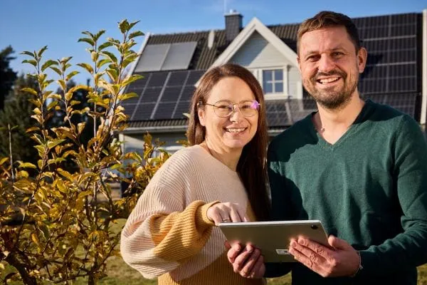 Paar vor Einfamilienhaus mit PV-Dach
