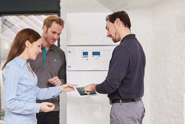 Beratungsgespräch Installateur mit 2 Kunden/innen an Inneneinheit Wärmepumpe