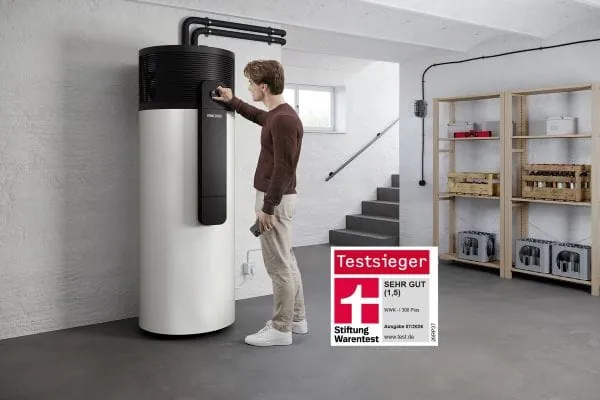 Junger Mann vpr Warmwasser-Wärmepumpe in Kellerraum