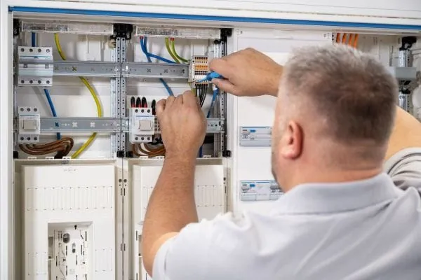 Elektriker arbeitet an einem Schaltschrank mit Zähleranlage